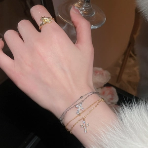 Detail of elegant gold star ring and layered zircon cross bracelets on a model hand