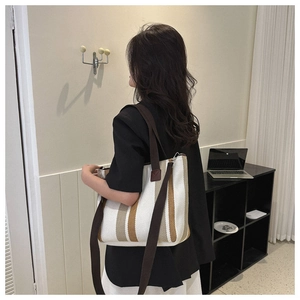 Lifestyle shot of a striped canvas tote bag worn as a shoulder bag for daily commuting