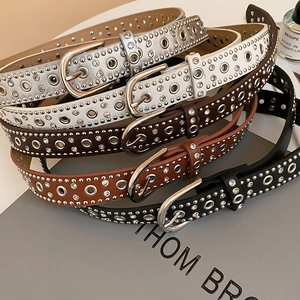Close-up of punk style leather belts with silver studs, eyelets and rhinestone details