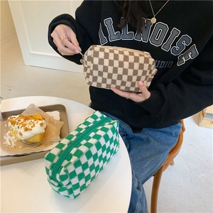 Detailed view of the thick knitted texture and zipper on checkered cosmetic bags