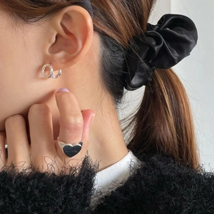 Silver twist hoop earrings and wide ring with black heart detail on female model