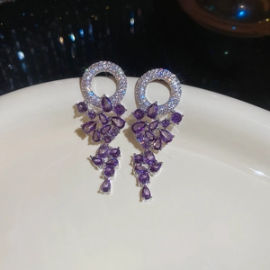 Détail de boucles d'oreilles argentées avec zircons violets sur céramique blanche