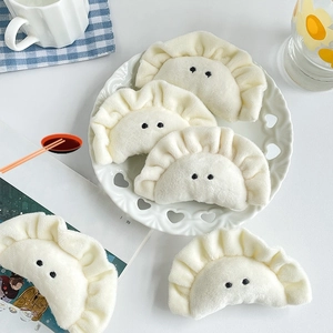 Flat lay of five white plush dumpling pendants with cute embroidered eyes on ins-style background