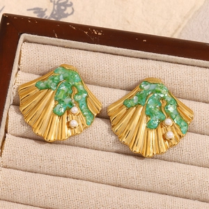 Detail shot of gold shell earrings with green stone inlay and white pearls in a jewelry box