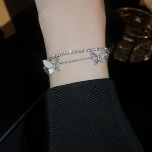 Detail shot of a double-layered zircon butterfly bracelet on a model's wrist with shiny metal