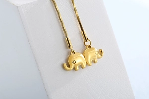 Macro detail of golden elephant pendants on a polished snake chain necklace