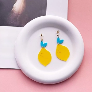 Acrylic lemon earrings with yellow fruit and blue leaves in a white decorative tray