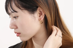 Close-up of a model wearing a minimalist golden stainless steel hoop earring
