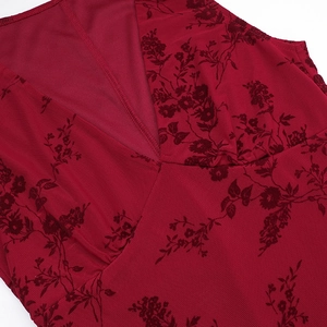 Détail d'une robe rouge à col en V avec des motifs floraux floqués rouge foncé sur fond blanc