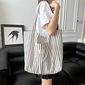 Lifestyle shot of large capacity blue striped canvas tote bag worn by a model in a room