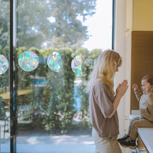 Close-up of rainbow prism window clings with circular holographic patterns on glass