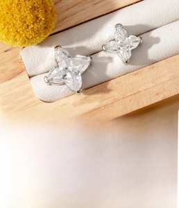 Detailed macro view of silver star zircon ear stud on a white jewelry cushion display