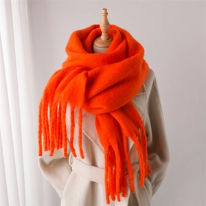 Gros plan d'une écharpe en mohair orange vif avec de longues franges et une texture chaude