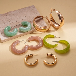 Detail view of 10-piece colorful acrylic and gold C-shaped hoop earrings on stone