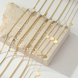 Collection of layered gold titanium steel necklaces with heart and star pendants on rocks