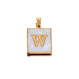 Close-up of golden square pendant with mother of pearl inlay and letter W engraving