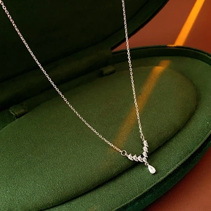 Close-up of a silver V-shaped necklace with teardrop zircon in a green jewelry box