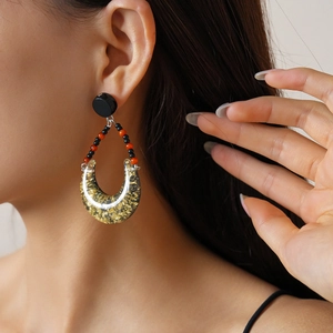 Detail of bohemian resin teardrop earrings with gold foil and beads worn by a model
