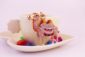 Detailed close-up of a purple rhinestone camel keychain with colorful enamel saddle decoration