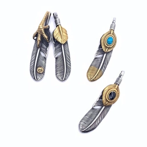 Detail of vintage eagle claw and turquoise feather pendants in gold and silver finish