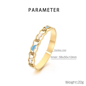 Detail of gold stainless steel bangle with blue enamel dolphins and palm tree design