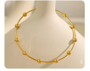 Close-up of a gold stainless steel beaded choker necklace displayed on a ceramic vase