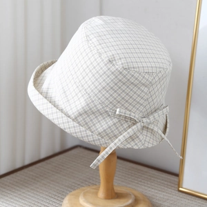 Detail of light yellow plaid sun hat with a bow tie ribbon on a wooden stand