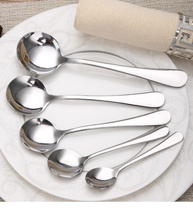 Set of five various sized thick stainless steel round spoons on a ceramic plate