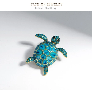 Détail macro d'une broche tortue dorée avec émail bleu et strass étincelants
