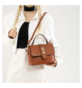 Brown vintage faux leather crossbody bag with a golden oval clasp shown on a model