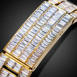 Macro detail of gold watch band featuring baguette-cut diamonds and luxury metal finish