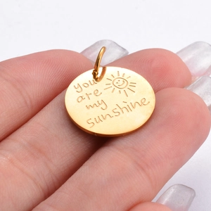 Vue macro d'un pendentif en acier doré gravé du texte you are my sunshine