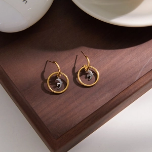 Elegante 18K Gold und Silber Edelstahl Vogel-Ohrhänger auf einem edlen Holztablett