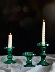 Detailed view of three vintage dark green glass candle holders with elegant ribbed texture
