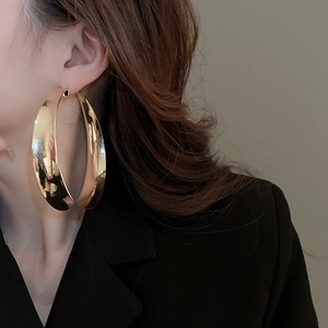 Close-up of oversized gold hoop earrings with polished mirror finish on a model