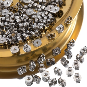 Detailed close-up of stainless steel butterfly earring backs in a gold metal tray