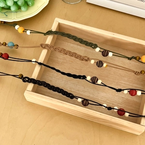 Detail of colorful woven lanyards with beads on a wooden tray in 45-degree view