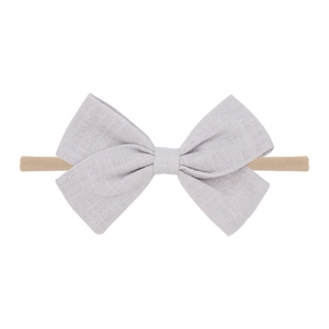 Detailed view of grey linen bow on beige nylon headband for babies and infants