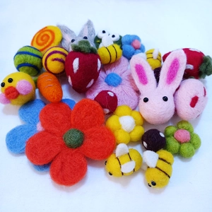 Flat lay of colorful wool felt DIY accessories featuring bees, flowers and rabbits