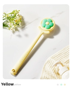 Detail of yellow long handle bath brush with a green flower-shaped soft bristle head