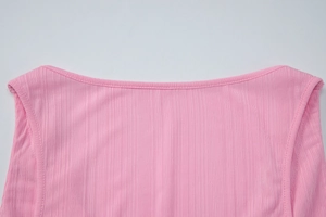 Dettaglio del gilet in maglia rosa con scollo a V e cuciture rifinite sulle spalle