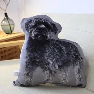 Detail of a lifelike Schnauzer-shaped plush pillow placed on a beige sofa cushions
