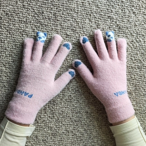 Close-up of pink knit gloves with blue panda motifs and heart designs on fingertips