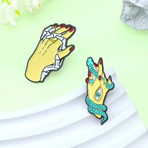 Creative enamel brooch set featuring interlocked skeleton hands and a snake wrapped around a hand