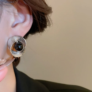 Detail eines silbernen Metallohrrings mit schwarzer Perle am Ohrläppchen eines Models