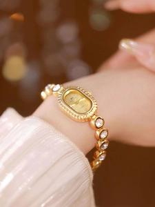 Elegant gold oval watch with crystal chain strap worn on wrist in warm soft lighting