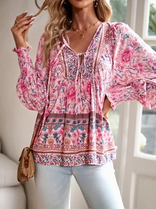 Detail of pink bohemian floral v-neck blouse with lantern sleeves and neck tie