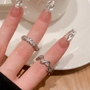 Close-up of geometric silver rings with zircon stones on a hand with luxury nail art