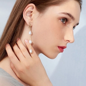 Baroque natural freshwater pearl long drop earrings with gold chains on female model