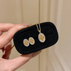 Detailed close-up of 18k gold plated jewelry set with fleur-de-lis and pavé zircons